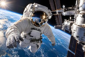 青い惑星を背に宇宙ステーションの外で浮遊する宇宙飛行士