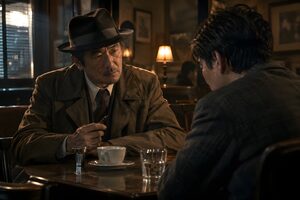薄暗い喫茶店で男性に話を聞く帽子の探偵