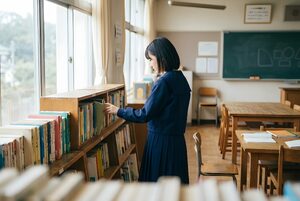 本棚の前で本を選ぶ女子生徒
