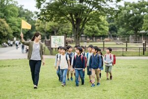 旗を持って子どもたちを引率する先生
