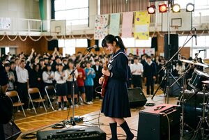 文化祭のステージでギターを弾く女子生徒