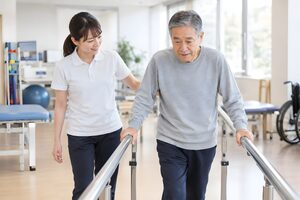 平行棒で歩行を支える理学療法士