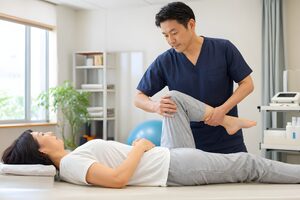 ベッドで膝のストレッチをする理学療法士