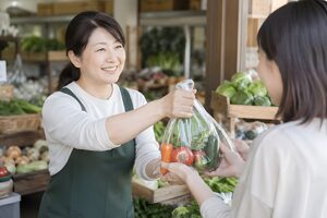 野菜を手渡す八百屋の店員