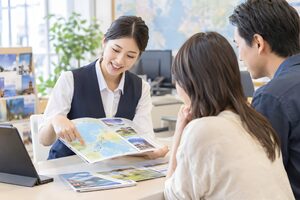 パンフレットで旅行プランを案内するスタッフ