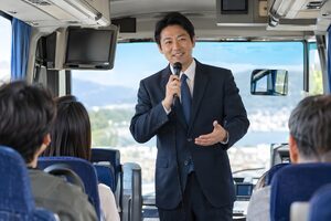 バスの中でマイクで案内する添乗員