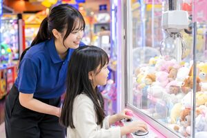 クレーンゲームの遊び方を教えるスタッフ