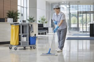 ロビーの床をモップがけする清掃員