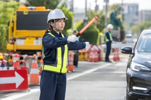 誘導灯で車を誘導する警備員
