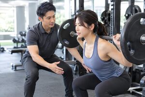 スクワットを補助するパーソナルトレーナー