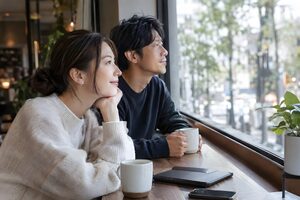 カフェの窓際に並んで座る30代のカップル