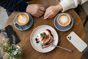 2つのラテとデザートが並ぶカフェのテーブル