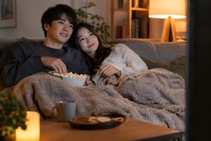 家のソファで映画を見るカップル