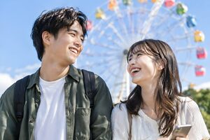 観覧車の前で笑い合うカップル