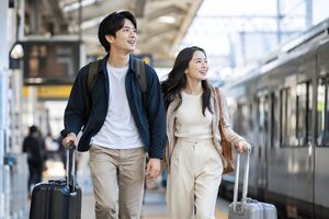 スーツケースを引いて駅を歩くカップル