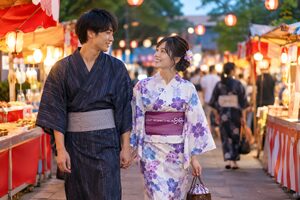 夏祭りの屋台通りを歩く浴衣のカップル