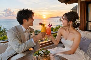 海を望むテラスで乾杯する新婚夫婦