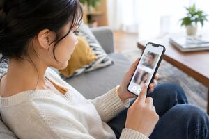 スマホでマッチングアプリを見る20代女性