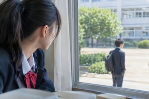 教室の窓から好きな人を見つめる女子高生