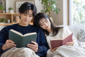 ソファで寄り添って本を読むカップル