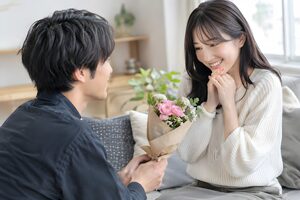 花束を差し出して仲直りするカップル