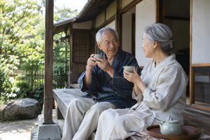縁側でお茶を飲む熟年夫婦