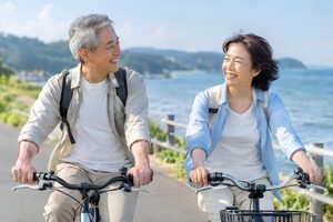 海沿いを並んでサイクリングする熟年夫婦