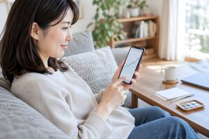スマホで資産の運用状況を確認する30代女性