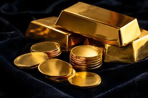 黒いベルベットの上の金の延べ棒と金貨