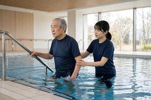 水中歩行のリハビリを受ける高齢男性