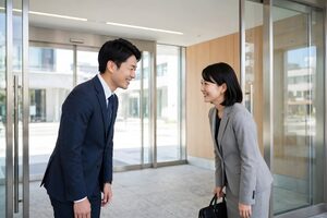 取引先の来客を笑顔で見送るビジネスパーソン