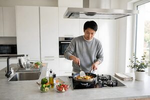 自宅のキッチンで野菜炒めを作る男性