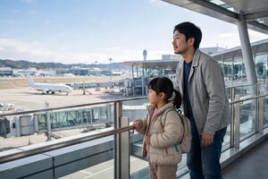 空港の展望デッキで飛行機を眺める父と娘