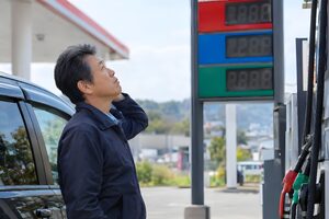 ガソリンスタンドの価格を見上げる50代男性