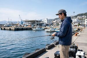 漁港の岸壁で釣りをする男性