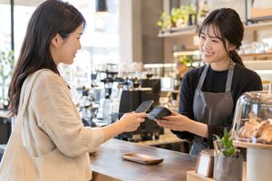 カフェでスマホ決済をする20代女性