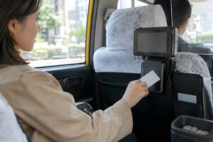 タクシーでタッチ決済をする乗客
