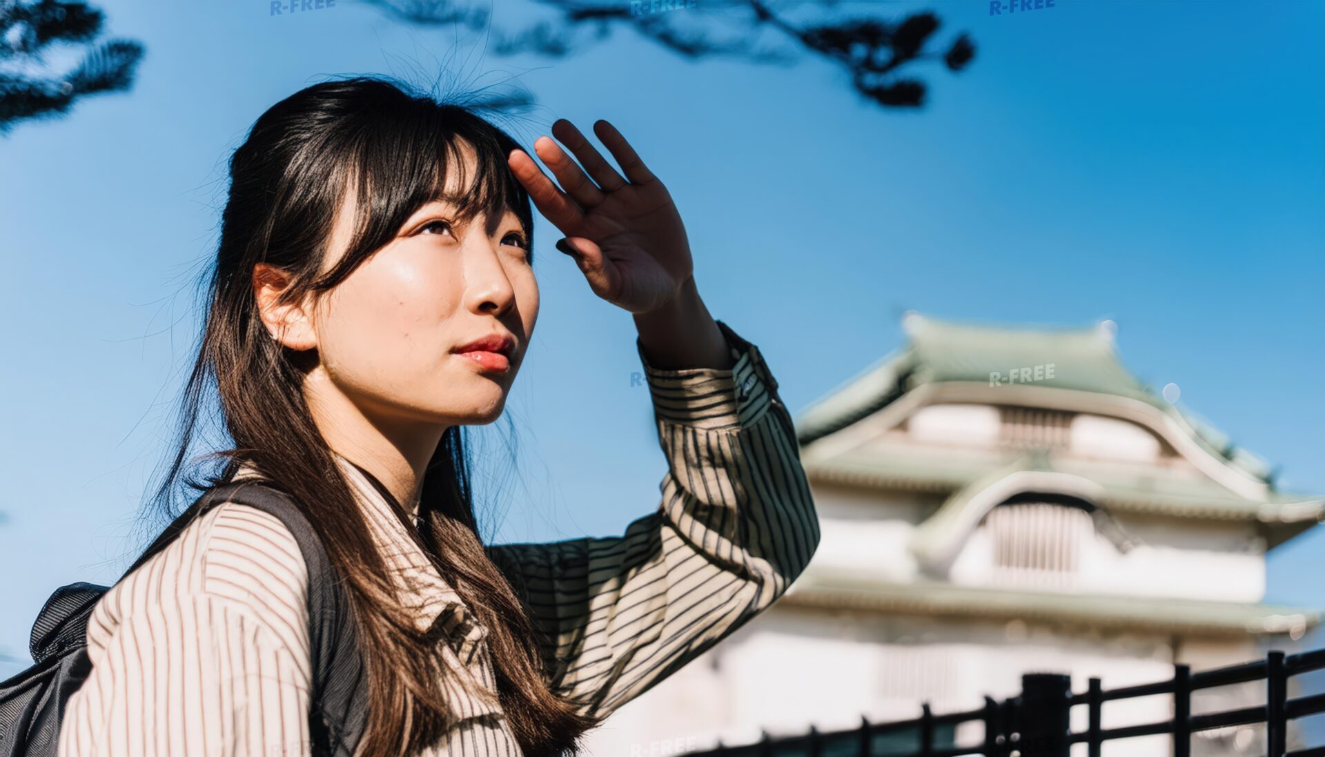 日本の城を背景に空を見上げる女性