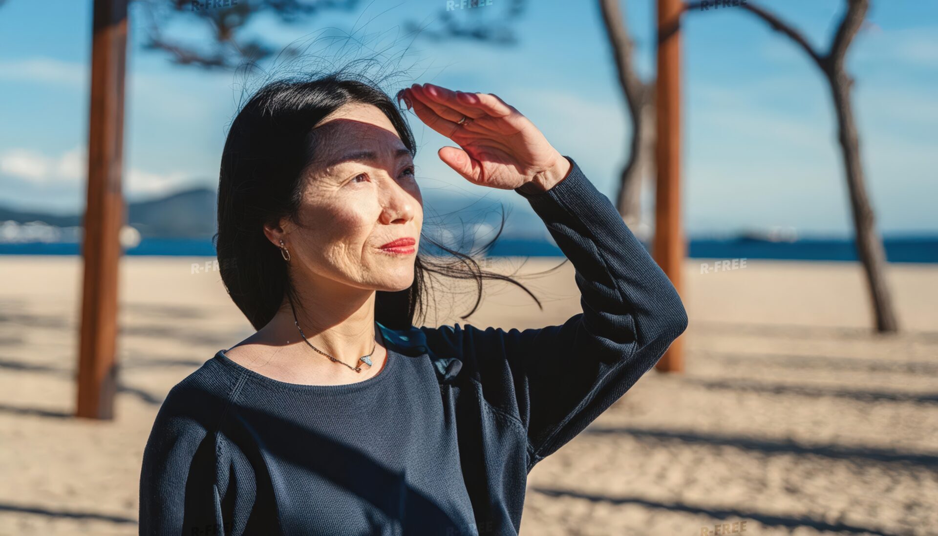 砂浜で風を感じながら遠くを見る女性