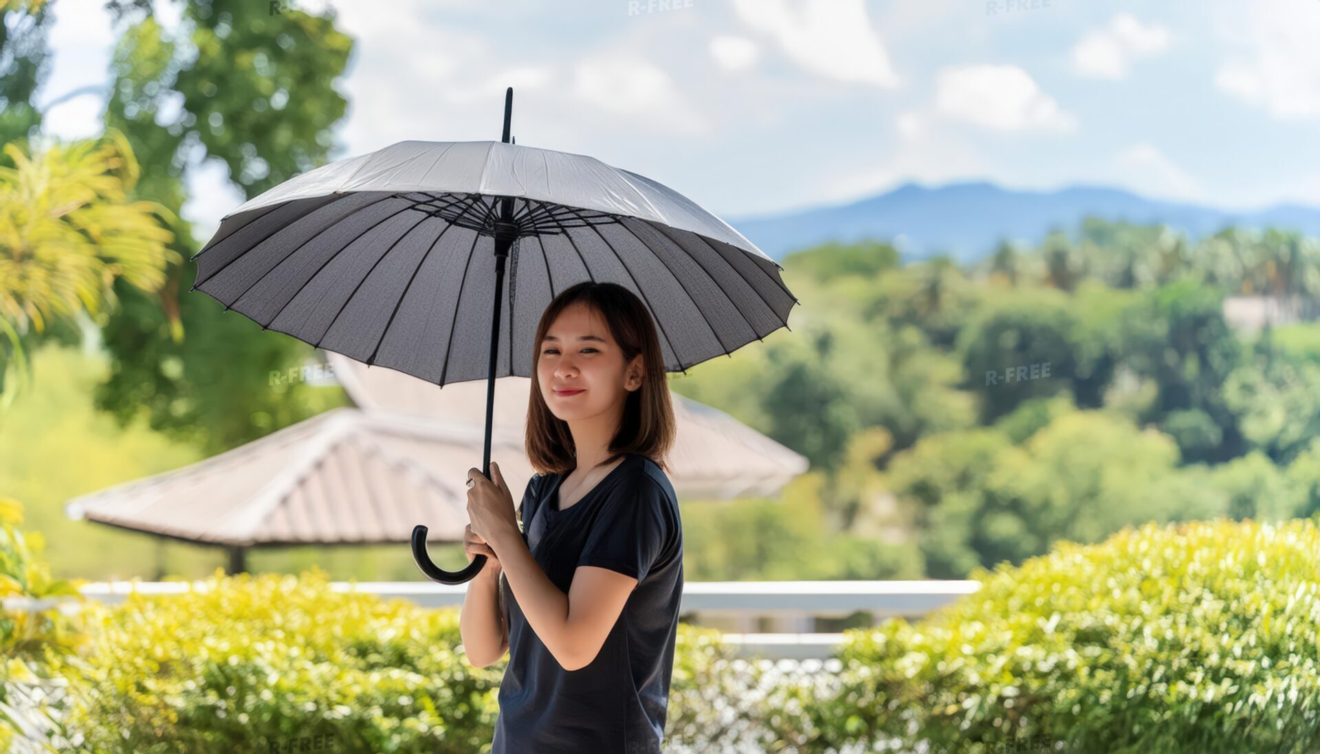 黒い日傘を持つ女性が屋外で微笑む