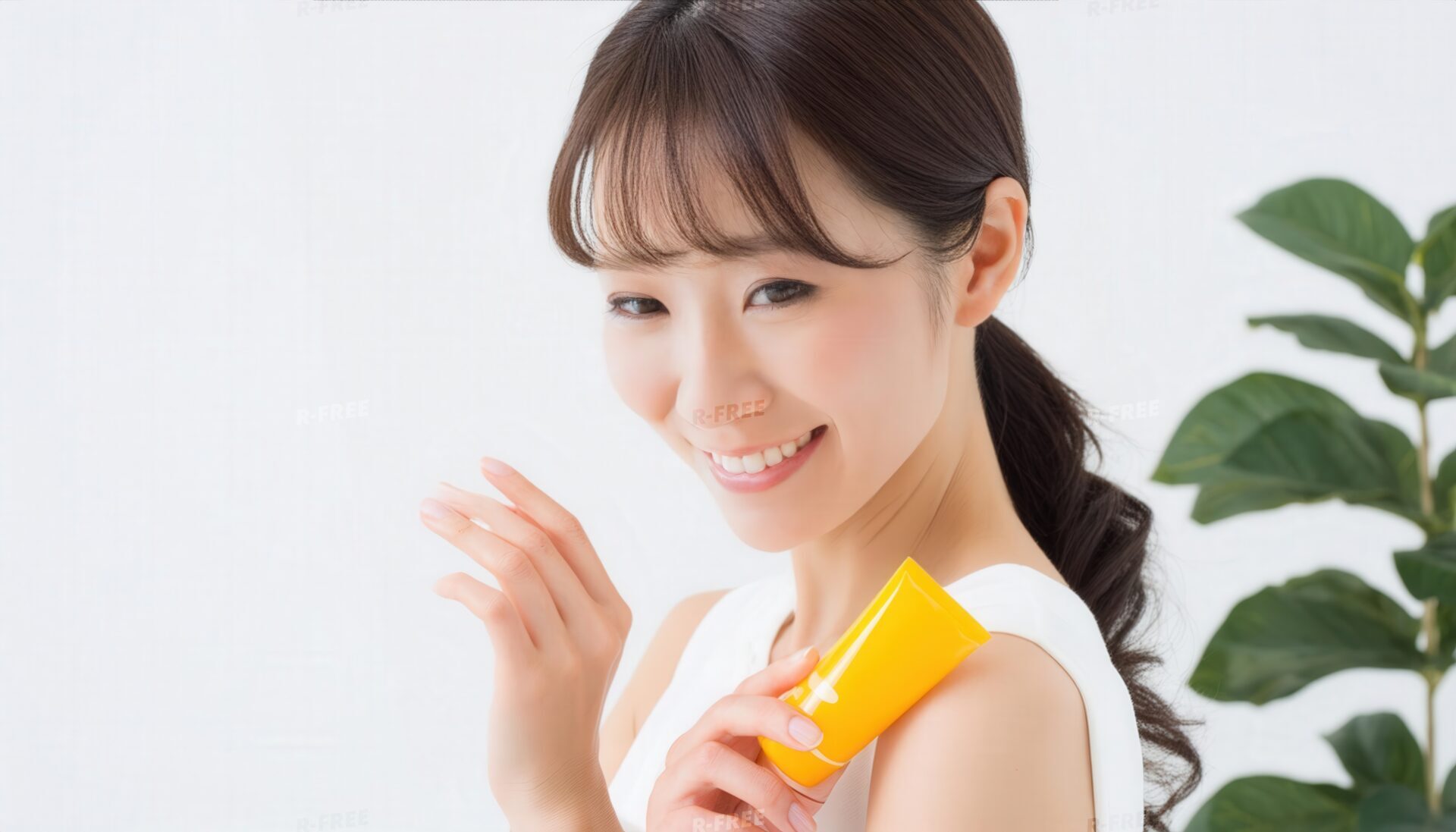 日焼け止めを手に肩へ添えて微笑むポニーテールの女性