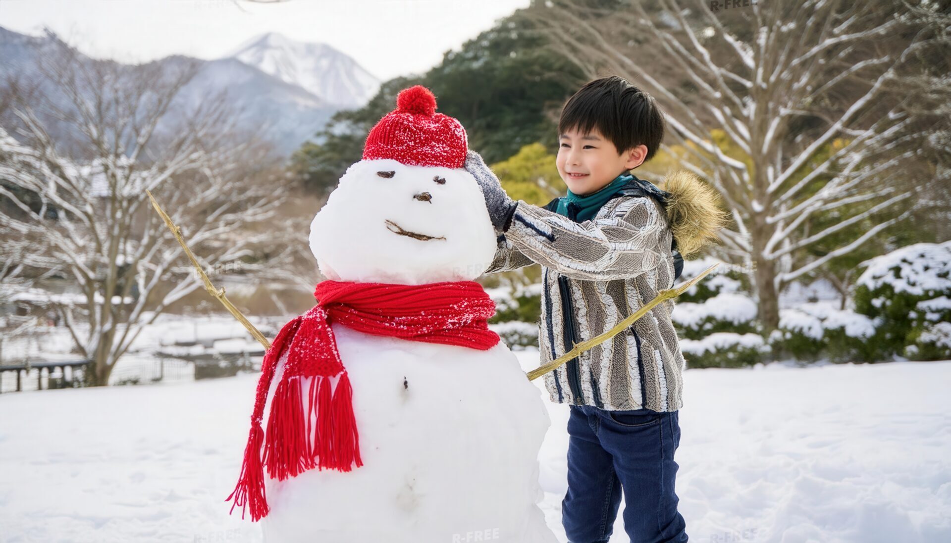 雪だるまと遊ぶ少年と山々を背景に微笑む男の子
