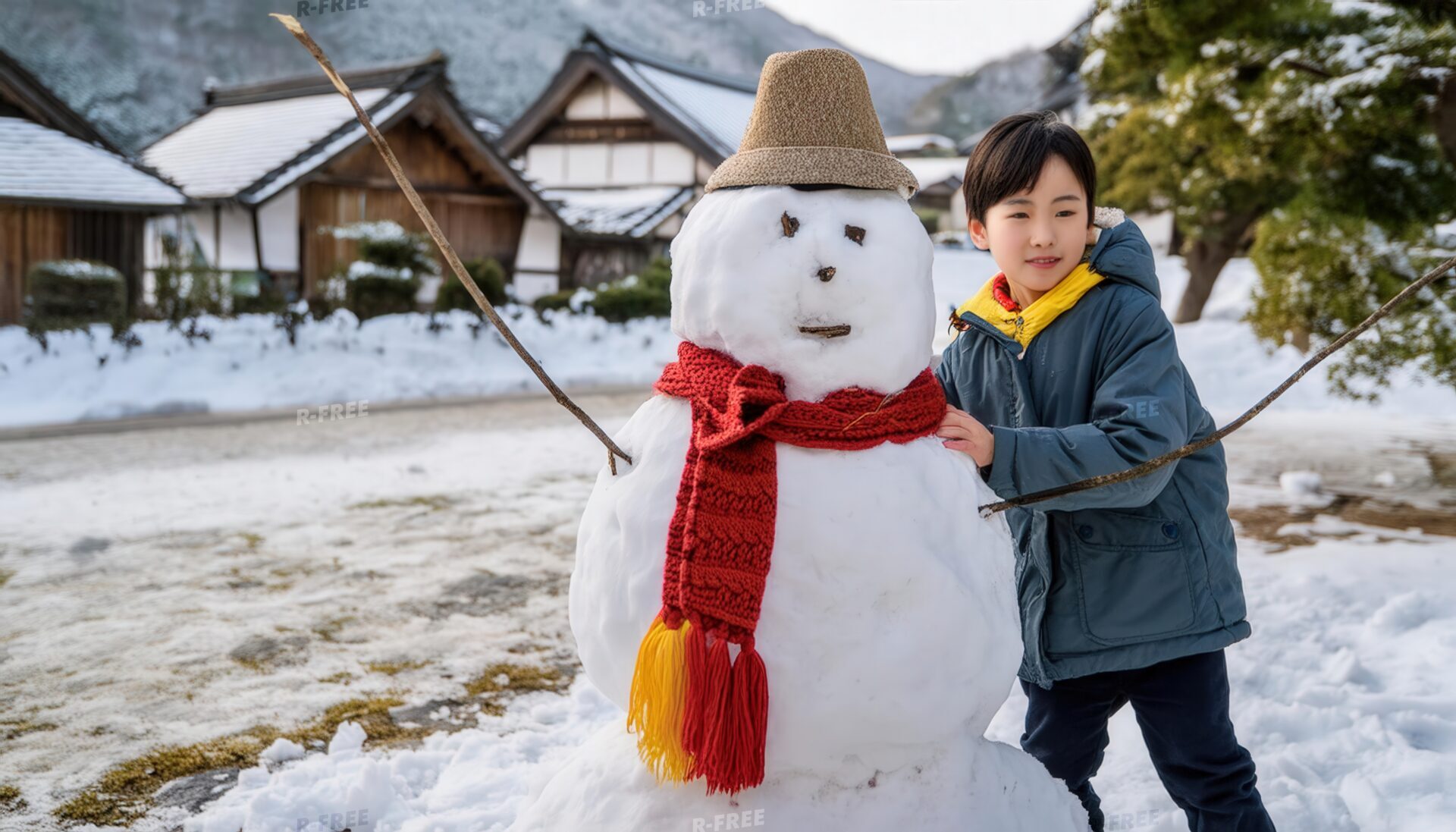 雪だるまと遊ぶ少年と雪化粧した民家の冬景色