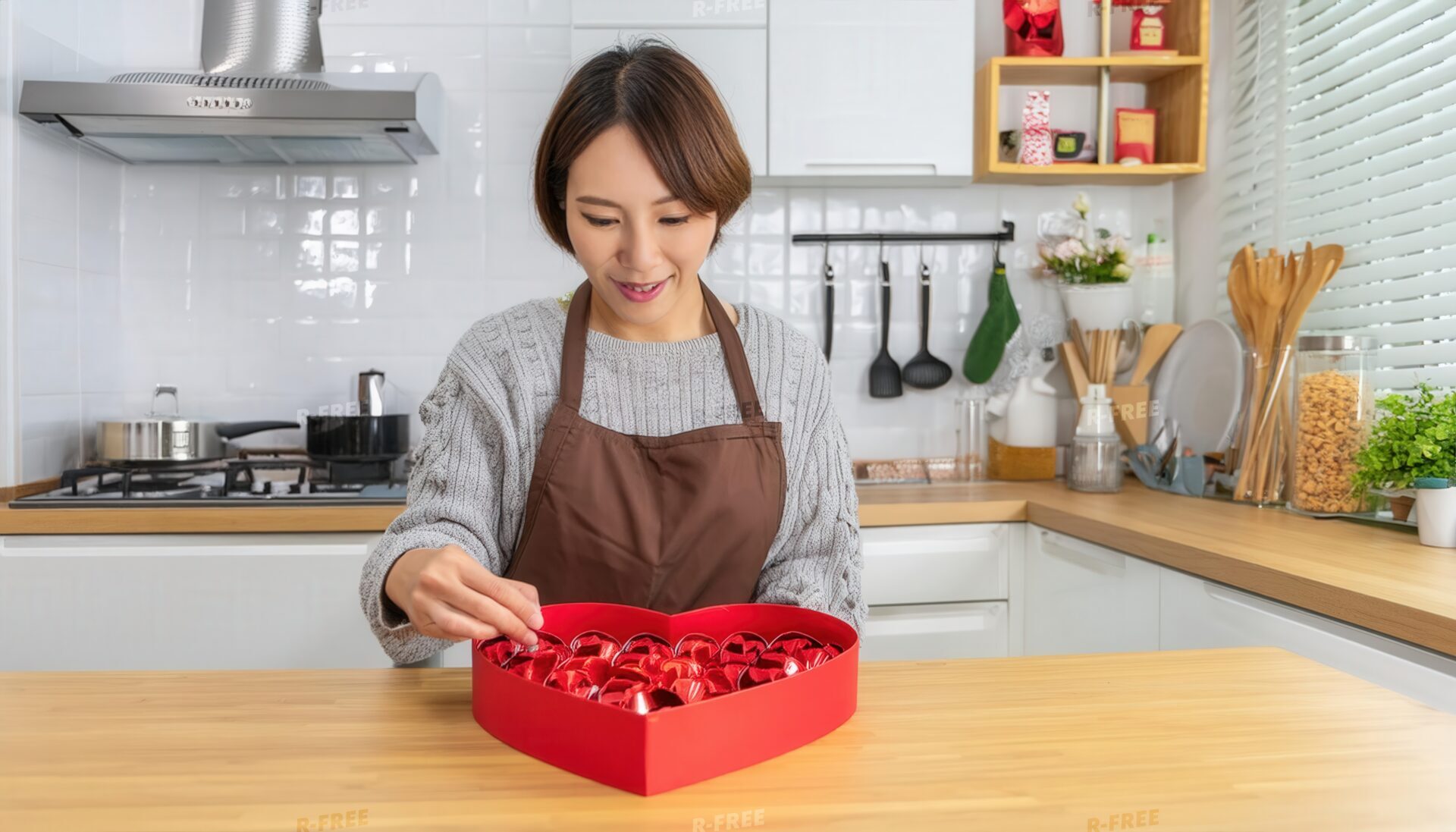 ハート型ボックスにチョコレートを詰める女性