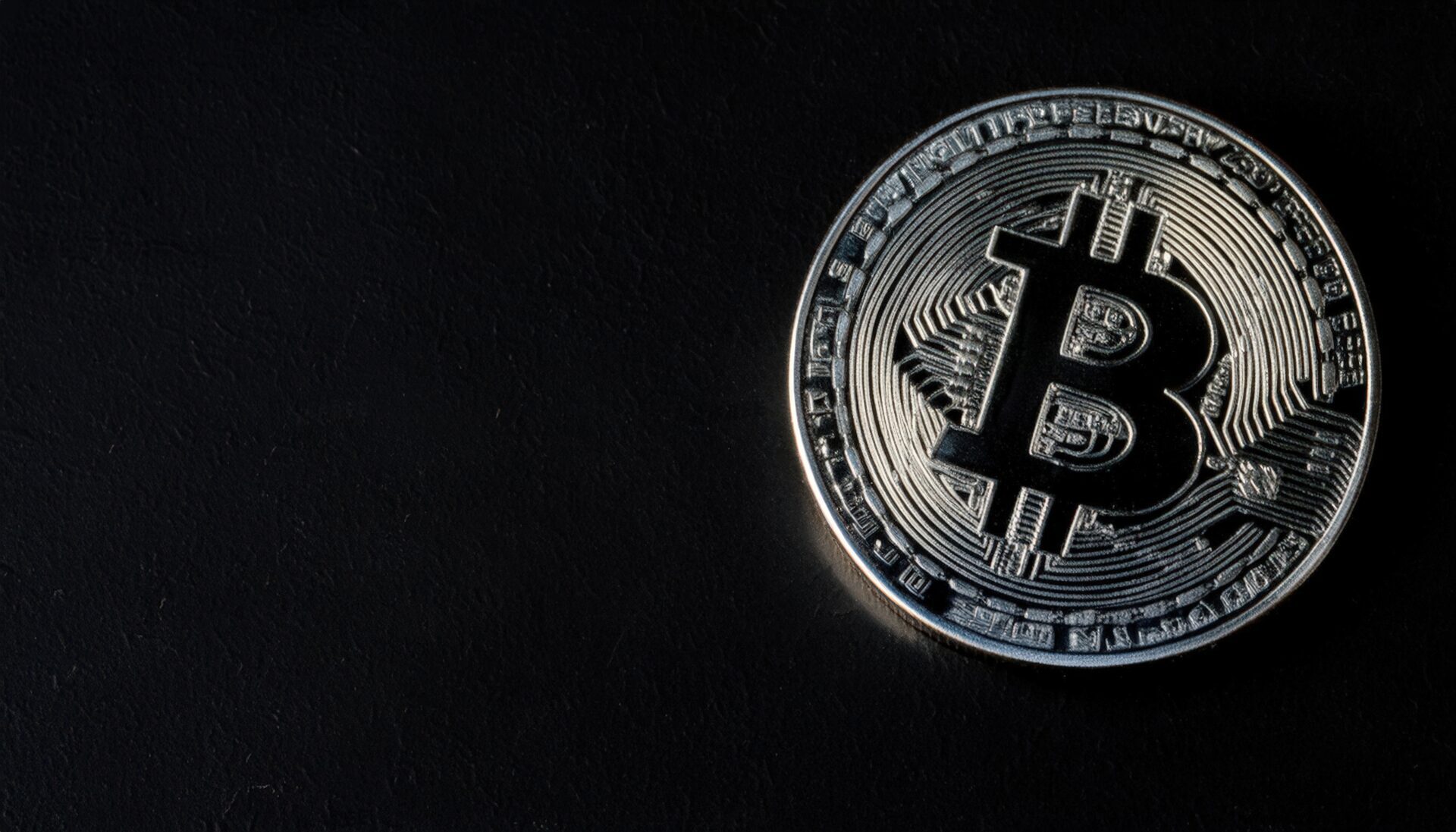 黒い背景に浮かび上がるシルバーのビットコイン