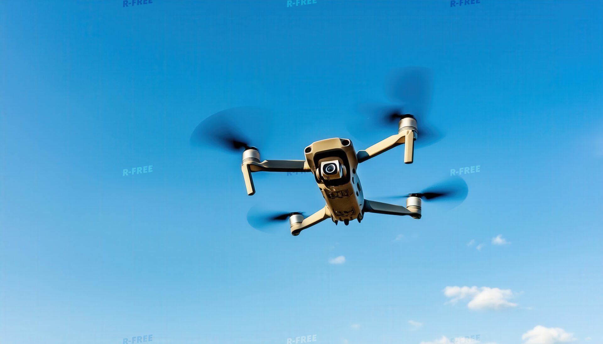 青空を飛行するドローンの機体と高速回転する4つのプロペラ