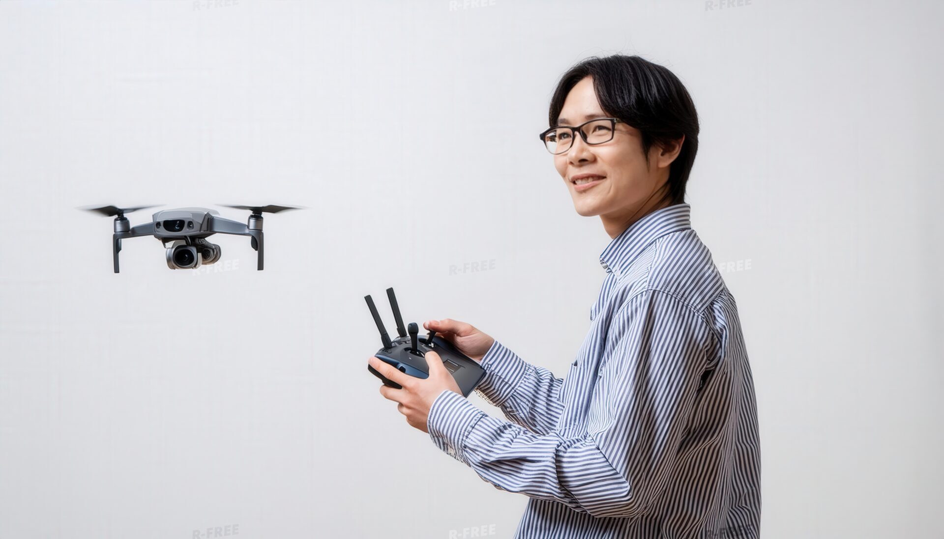 室内でドローンを操作する眼鏡をかけた男性