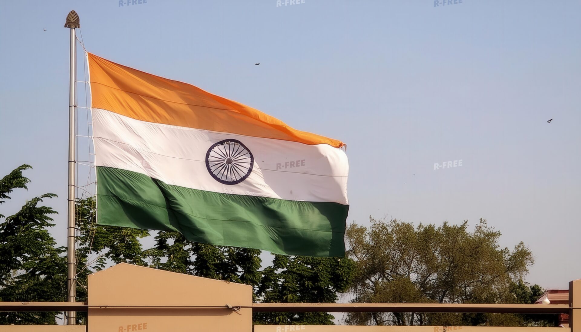 木々と構造物を背景に風になびくインド国旗