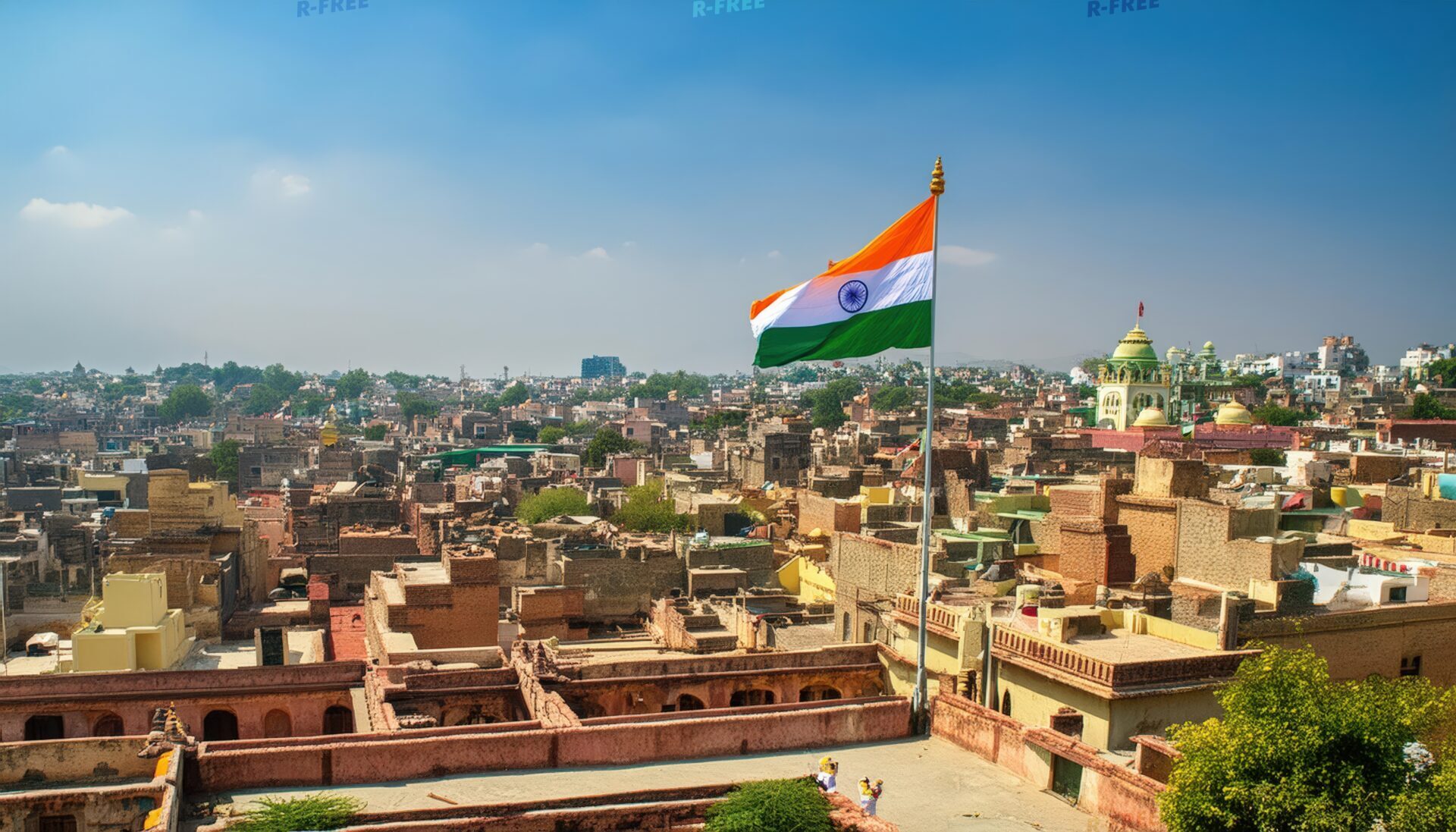 褐色の家々を俯瞰する都市と風になびくインド国旗