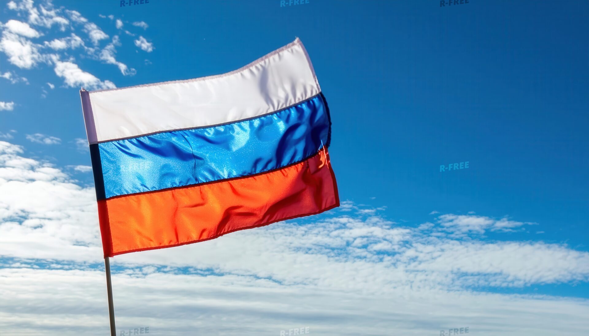 青空と薄雲を背景に風になびくロシア国旗